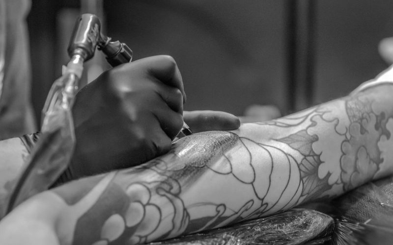 Grayscale Photo of Person Applying Tattoo